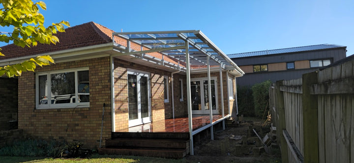 Patio addition under construction on a house with clear blue sky.